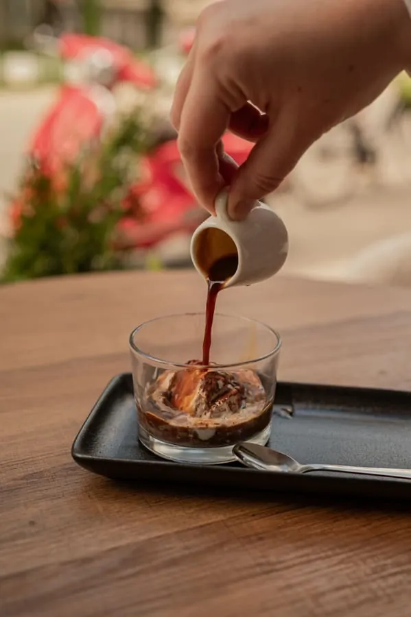 Espresso poured from a small jug over a scoop of ice cream in a glass